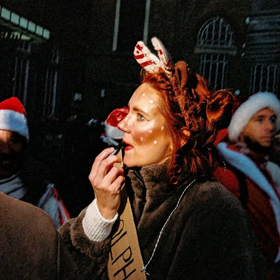 Woman putting on lipstick wearing christmas outfit
