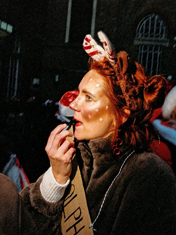 Woman putting on lipstick wearing christmas outfit