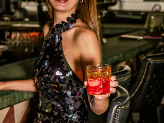 Lady enjoying a cocktail beside the bar at Sophies Rooftop Restaurant in The Dean hotels