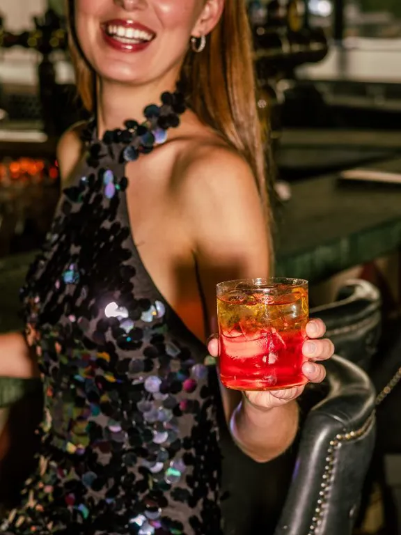 Lady enjoying a cocktail beside the bar at Sophies Rooftop Restaurant in The Dean hotels